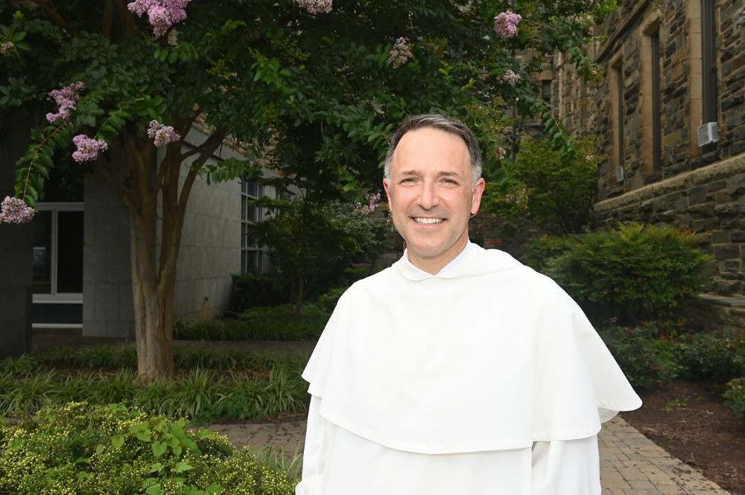 Father Aquinas in front of a tree smiling